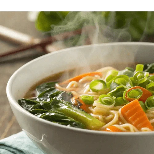 A steaming bowl of Hello Fresh ramen with colorful vegetables and green onions.